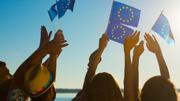 Menschen mit erhobenen Händen schwenken Europaflaggen